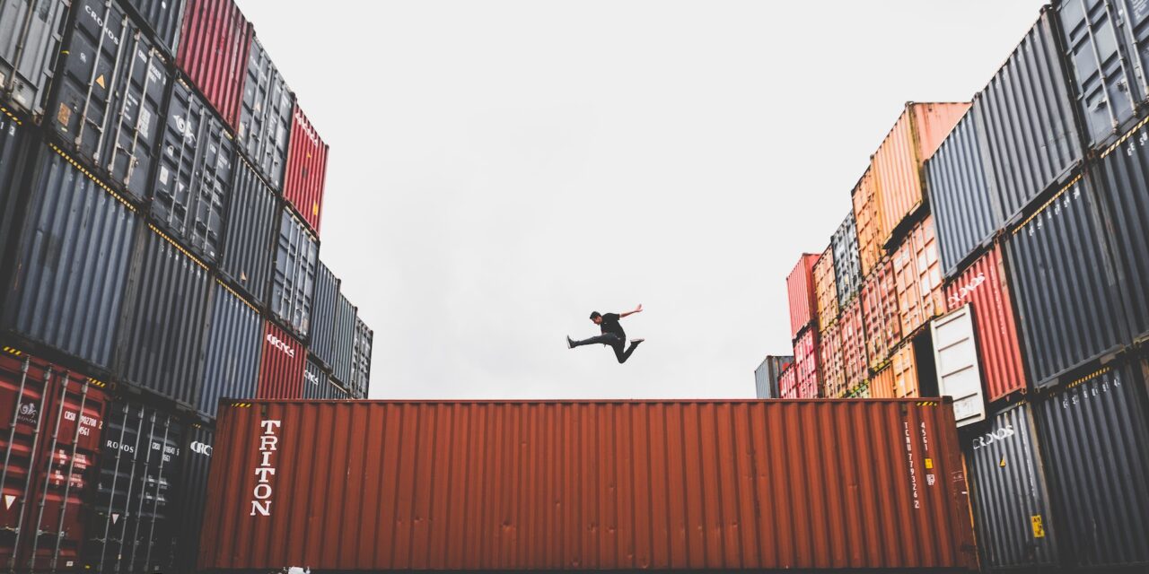A man jumps over an industrial container.