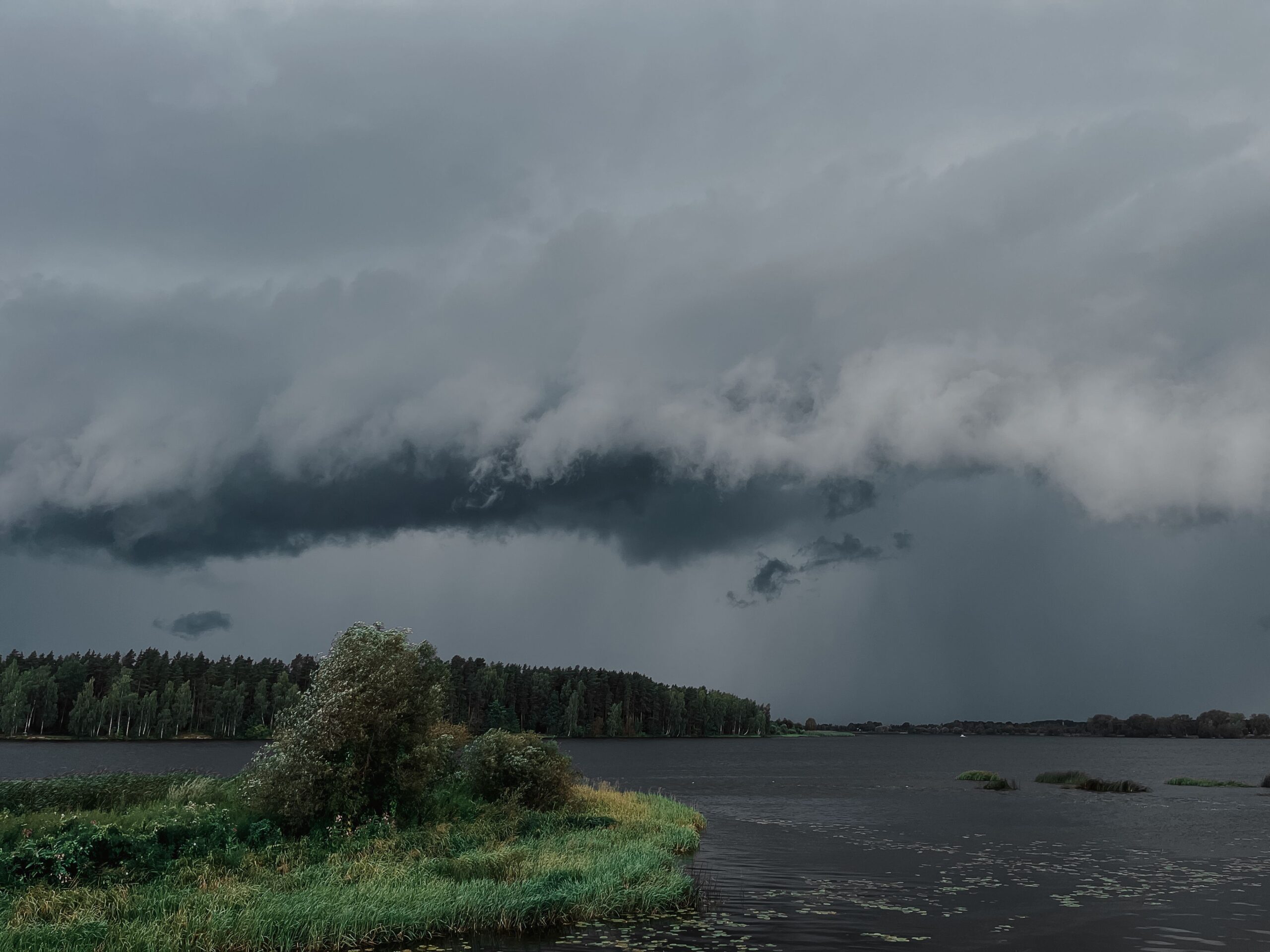 Dark, gray storm clouds gather over land and water.